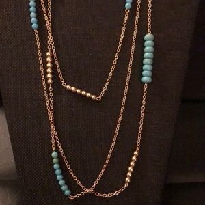 Gold chained necklace with teal color beans.